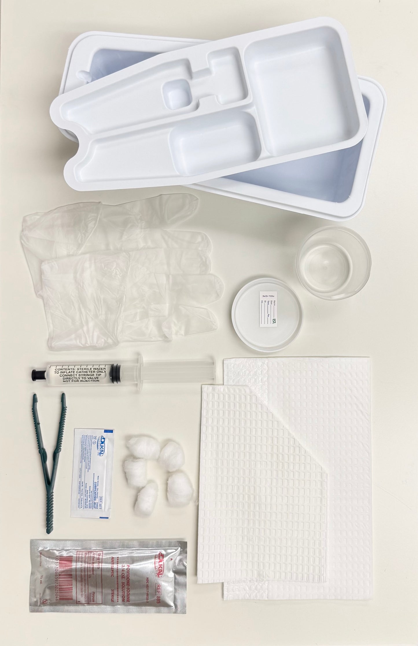 LSL FOLEY CATHETERIZATION TRAY W/O CATHETER, PREP BALLS, PLASTIC FORCEPS, PVP SOLUTION, 10 CC SYRINGE (pre-filled w/sterile water), VINYL POWDER FREE GLOVES, LUBRICANT JELLY, MOISTURE PROOF UNDER BUTTOCKS DRAPE, FENESTRATED DRAPE, SPECIMEN CONTAINER.